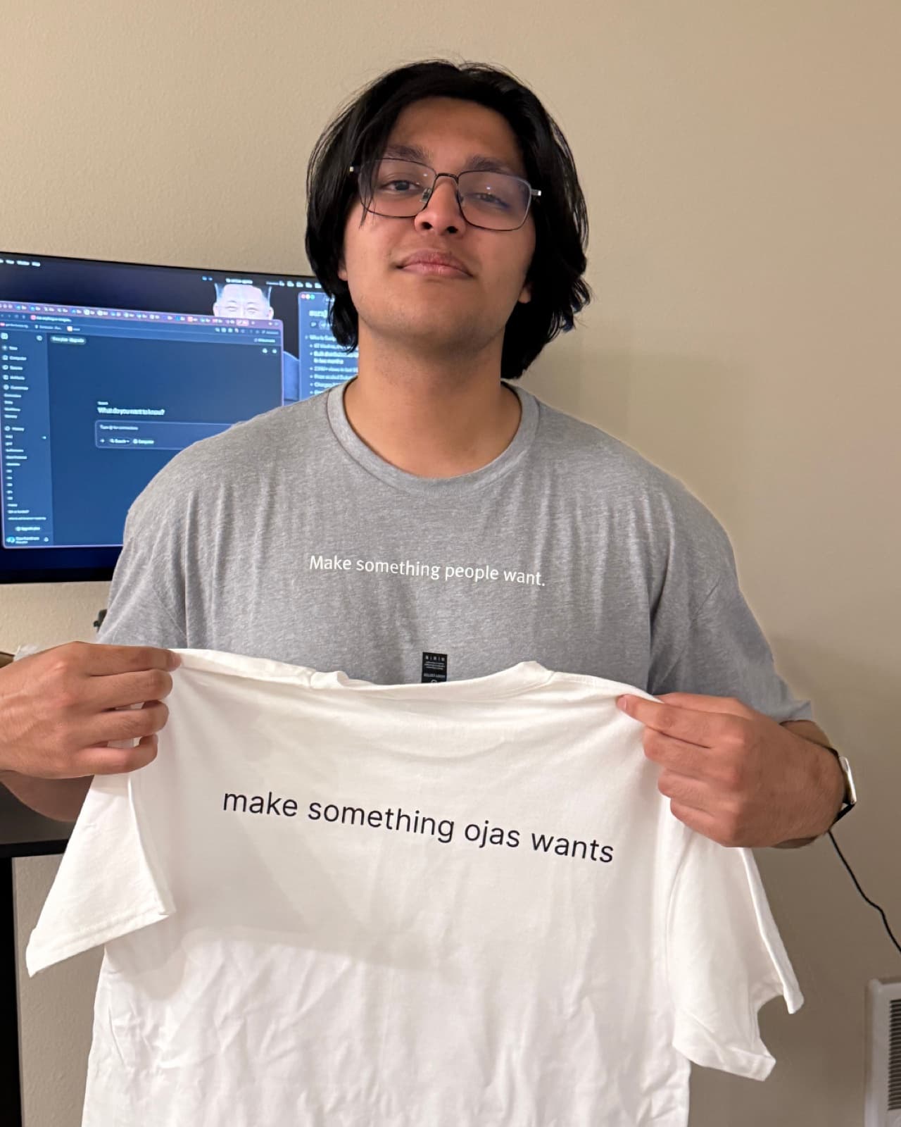 An OpenTrade team member holding a 'make something ojas wants' t-shirt